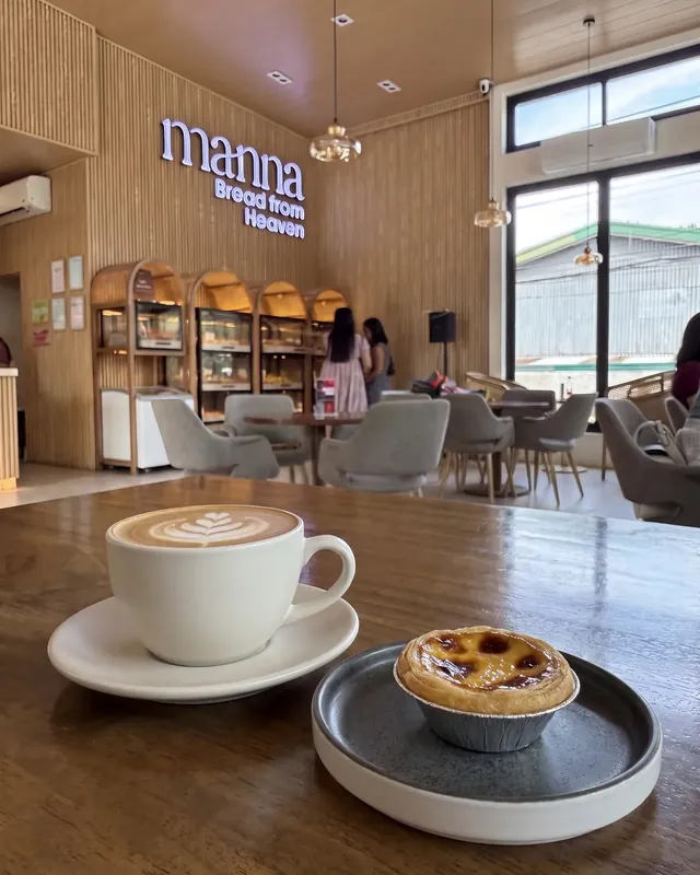 A hot latte and a Portuguese egg tart on a walnut table